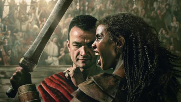 Schreiende Schwarze Gladiatorin hält in Arena Schwert in die Höhe