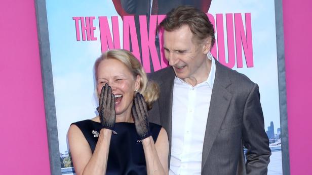 eine herzlich lachende Pamela Anderson neben Liam Neeson bei einem Pressetermin