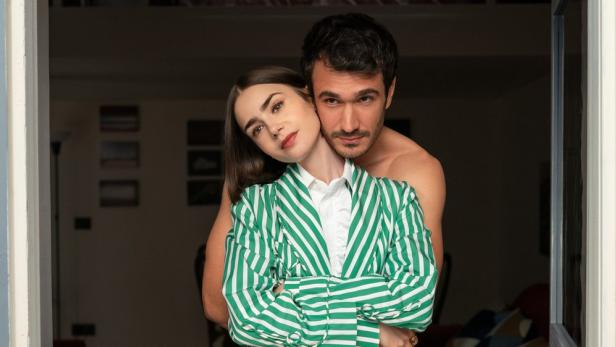 Lily Collins als Emily mit Italiener Marcello, der mit nacktem Oberkörper hinter ihr steht