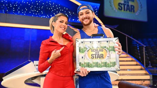 Sylvie Meis steht neben Riccardo Simonetti, der einen Geldkoffer hält