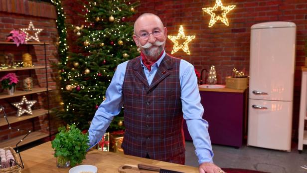 Horst Lichter steht in weihnachtlich geschmückter Küche