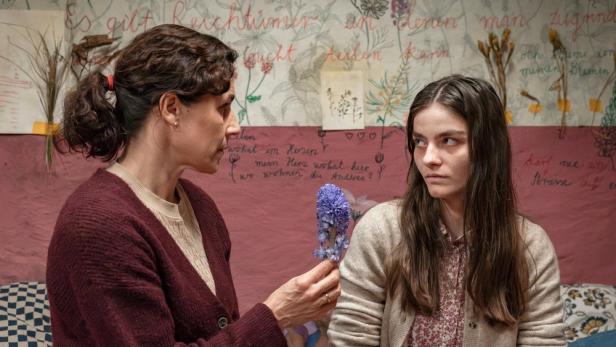 Frau hält Mädchen eine Blume hin