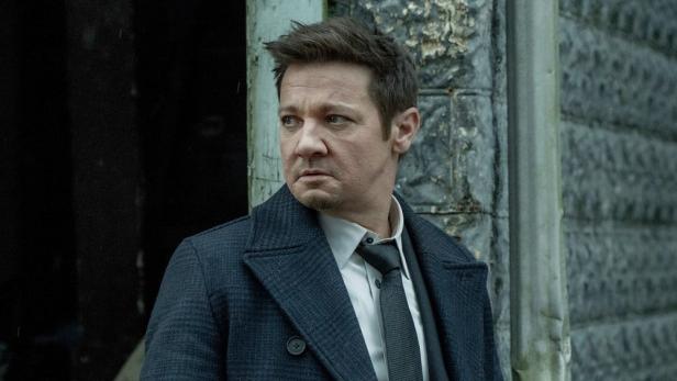 Jeremy Renner steht in seiner Serienrolle an einer Gebäudeecke