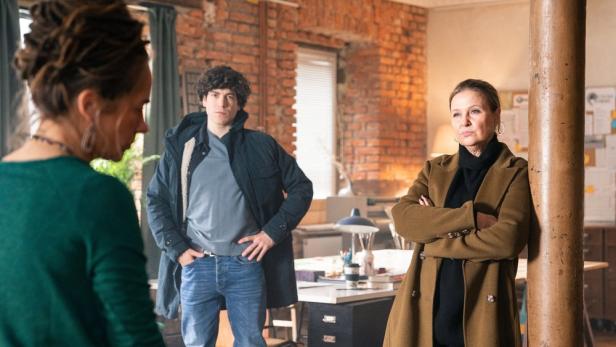 Mann und Frau stehen in einem Büroraum einer anderen Frau gegenüber
