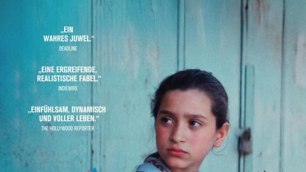 Ein Schulmädchen hält einen Hahn in Händen