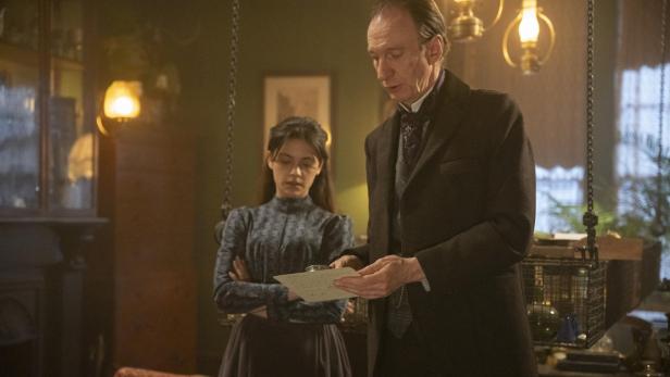 Blu Hunt und David Thewlis betrachten ein Blatt in ihren Serienrollen