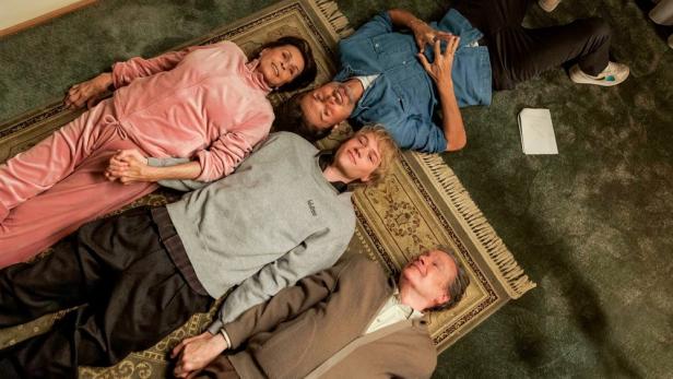 Großeltern und ihr Enkelsohn liegen auf dem Rücken auf einem Teppichboden