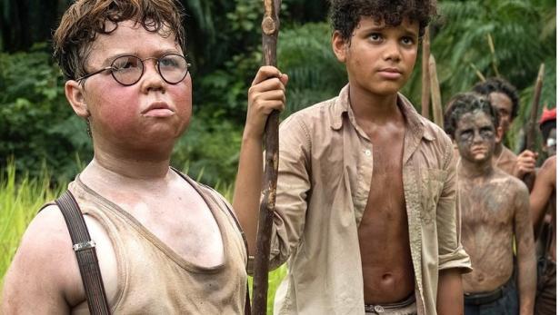 Eine Gruppe von mitgenommen wirkenden Kindern steht vor Palmenkulisse