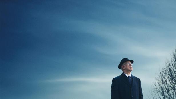 Mann steht einsam in Landschaft mit kahlen Bäumen im Hintergrund