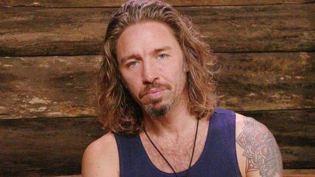 Gil Ofarim steht vor einer Holzwand