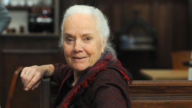 Ursula Erber sitzt auf einer Holzbank in einem Lokal