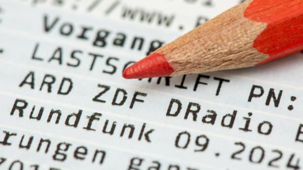 Roter Buntstift liegt auf Rundfunkrechnung in Großaufnahme