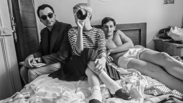 Guillaume Marbeck als Godard, Zoey Deutch als Jean Seberg und Aubry Dullin als Jean-Paul Belmodo auf einem Bett