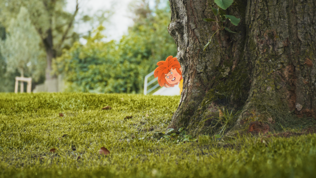 Kobol Pumuckl blickt hinter einem Baum hervor