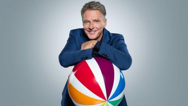 Jörg Pilawa stützt sich auf bunten Sat1-Logo-Ball
