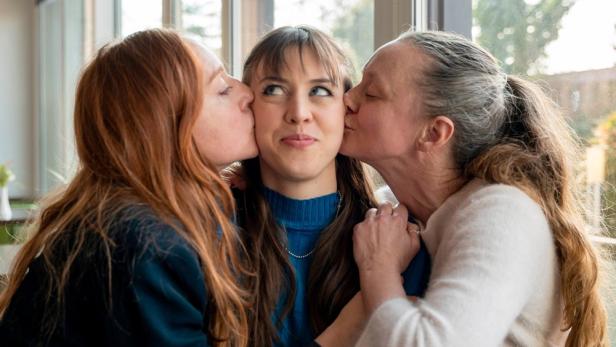 Alina Schaller erhält in Filmrolle von Brigitte Hobmeier und Gerti Drassl gleichzeitig einen Kuss auf jede Wange