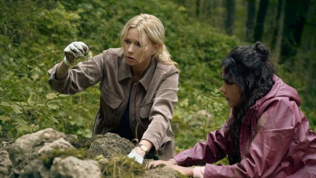 Zwei Frauen suchen nach Spuren unter Steinen im Wald