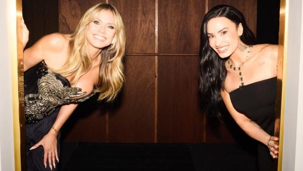 Heidi Klum und Demi Lovato blicken aus einer Aufzugskabine