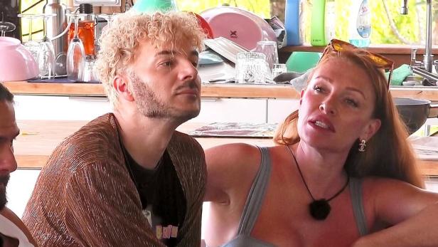 Sam Dylan und Georgina sitzen vor einer Küchenzeile