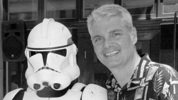 Ein Mann steht lächelnd neben einer Person in einer Stormtrooper-Rüstung aus Star Wars.
