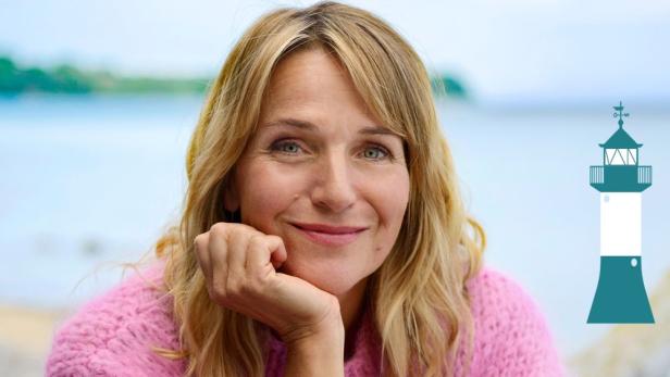 Eine Frau mit blondem Haar und rosa Pullover lächelt am Wasser, daneben ist eine stilisierte Illustration eines Leuchtturms.