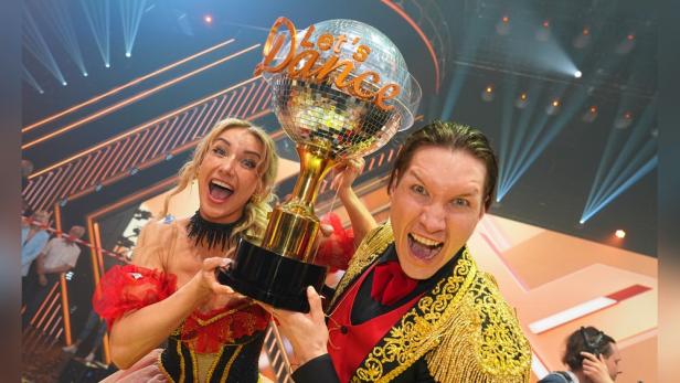 Zwei jubelnde Personen halten eine "Let's Dance"-Trophäe in die Höhe.