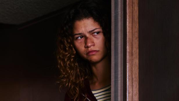Zendaya in ihrer Euphoria Rolle als Rue blickt finster hinter einem Türstock hervor