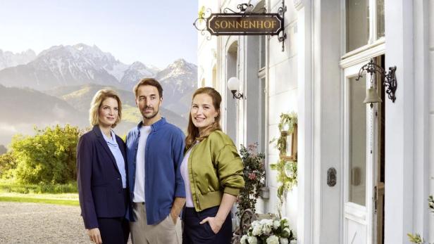 Drei Personen stehen vor dem Haus „Sonnenhof“ vor Alpenpanorama.