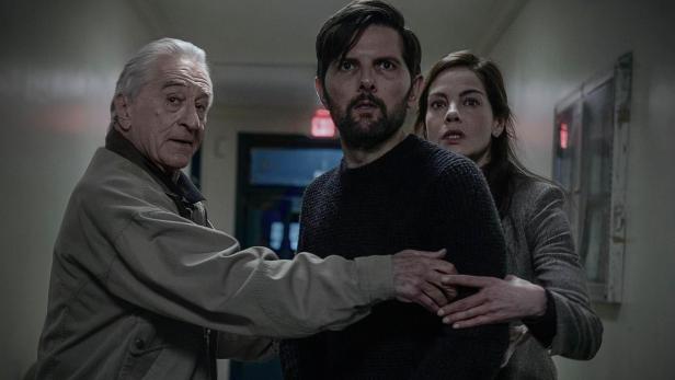 Robert De Niro, Adam Scott und Michelle Monaghan stehen mit besorgten Mienen in einem dunklen Flur.