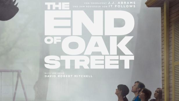 Filmplakat zu „The End of Oak Street“ mit Anne Hathaway und Ewan McGregor, die in einer nebligen Vorstadt vor einem riesigen Dinosaurierkopf stehen.