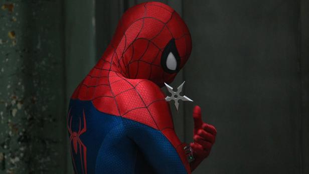 Spider-Man betrachtet nachdenklich einen silbernen Wurfstern, den er in der Hand hält.