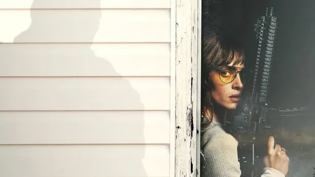 Filmposter zu Onslaught von Adam Wingard mit Adria Arjona, die mit einem Gewehr durch ein Fenster blickt.
