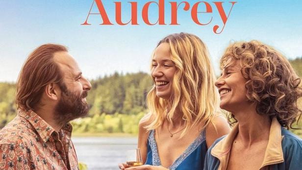 Filmplakat für „Frühstück bei Audrey“ mit Vincent Macaigne, Zoé Marchal und Cécile De France, die lachend mit Weingläsern vor einem See stehen.