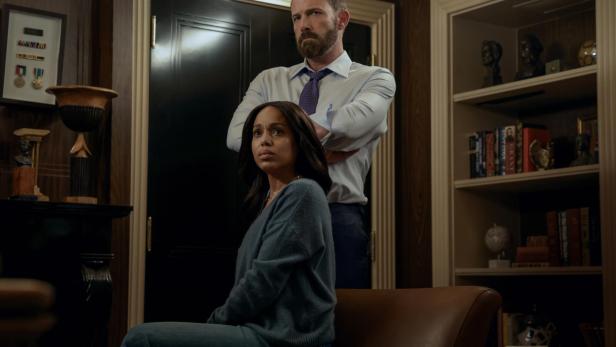 Ben Affleck steht mit verschränkten Armen hinter der sitzenden Kerry Washington in einem eleganten Büro.