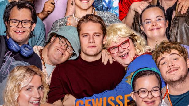 Eine diverse Gruppe von Menschen lächelt gemeinsam auf dem Filmplakat zu „Das gewisse Etwas“ unter der Regie von Marc Rothemund.