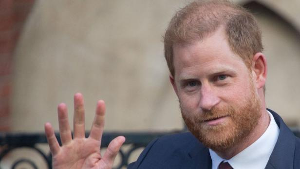 Porträt von Prinz Harry im Anzug, der mit erhobener Hand winkt.