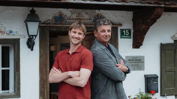 Zwei Männer stehen mit verschränkten Armen vor der Bergdoktor-Praxis von Dr. med. Martin Gruber in Faistenbichl 15.