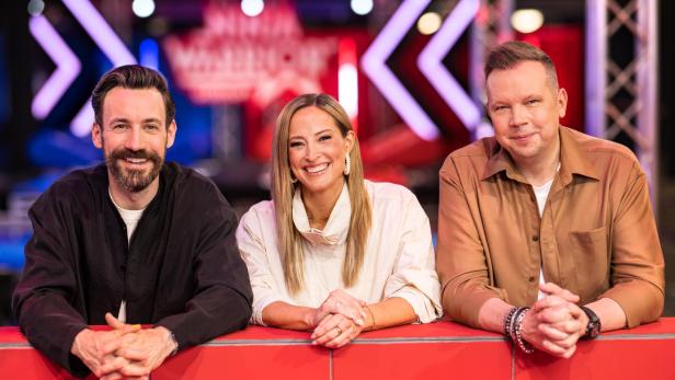 Jan Köppen, Anna Fleischhauer, Wolff Fuss sitzen lächelnd vor dem Ninja Warrior Germany-Logo.