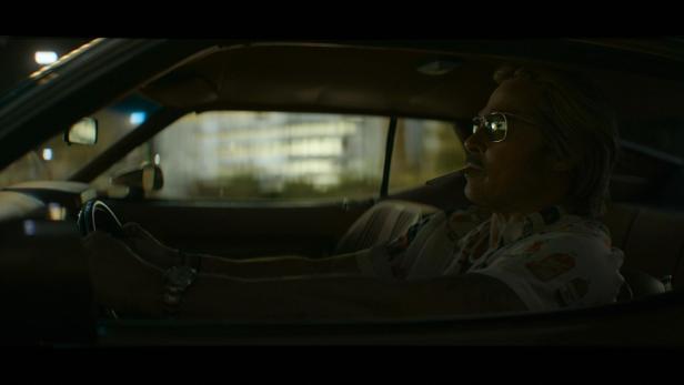 Brad Pitt fährt bei Nacht in einem Auto und raucht eine Zigarette.