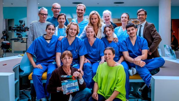 Die Besetzung und Crew der Serie „Pflegeleicht“ posieren gemeinsam in einem Krankenhausset.