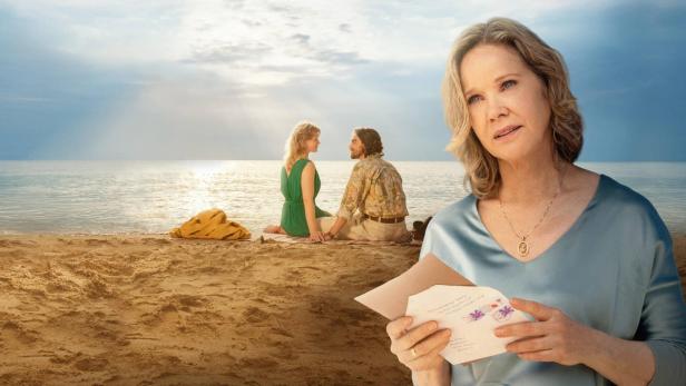 Im Vordergrund hält eine nachdenkliche ältere Frau einen Brief, während im Hintergrund ein junges Paar am Strand sitzt.