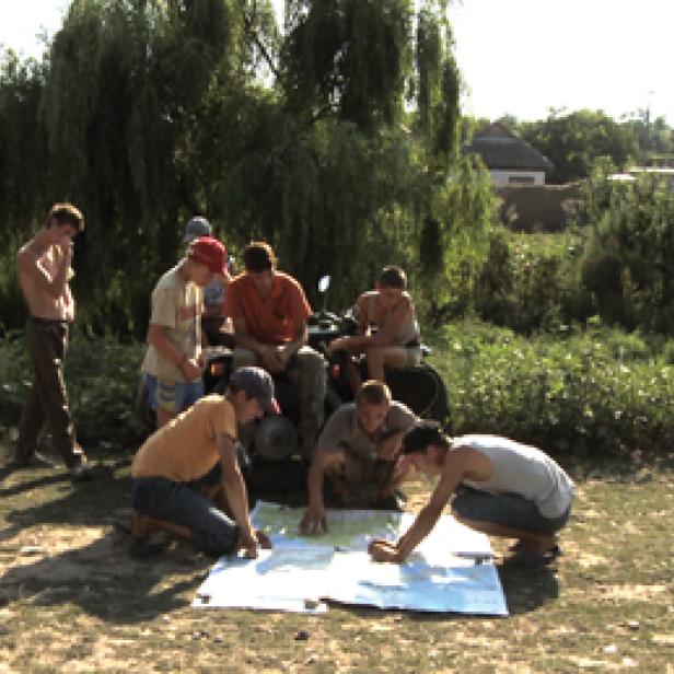 Eine Gruppe junger Männer studiert eine Karte neben einem Quad im Grünen.