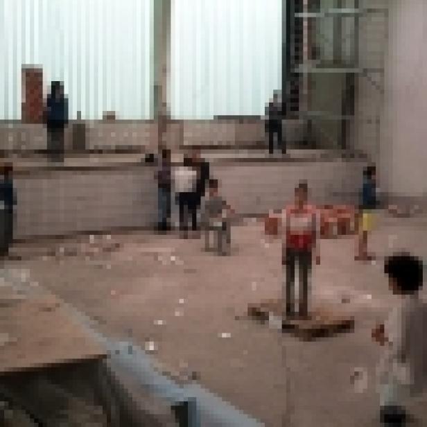 Eine Gruppe von Kindern spielt in einem unordentlichen Raum mit Bauschutt.