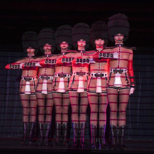 Eine Gruppe von Tänzerinnen in Gardeuniformen auf einer Bühne.
