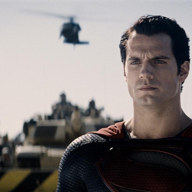 Henry Cavill als Superman vor Panzern und Hubschraubern.