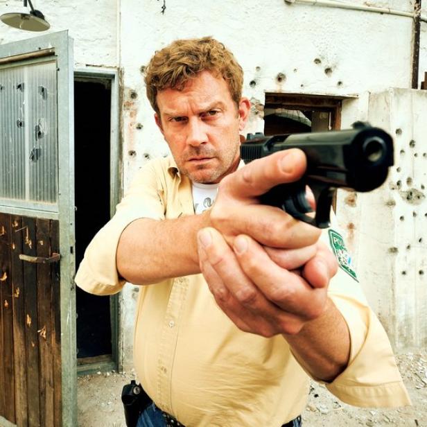 Sebastian Bezzel in einem Eberhoferkrimi mit einer Waffe in der Hand.
