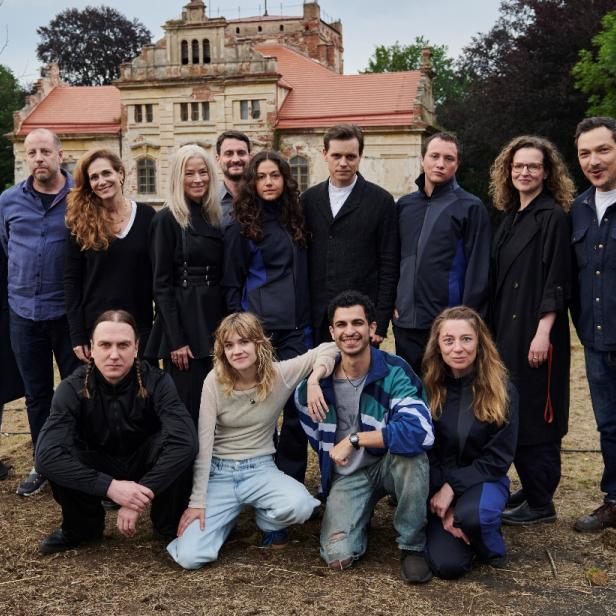 Eine Gruppe von Schauspieler:innen steht vor einem alten Schloss für den Drehstart von „City of Blood“.