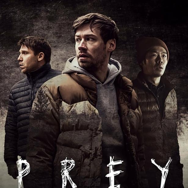 Das Filmplakat für „Prey“ zeigt drei Männer in Winterkleidung vor einem dunklen Hintergrund.