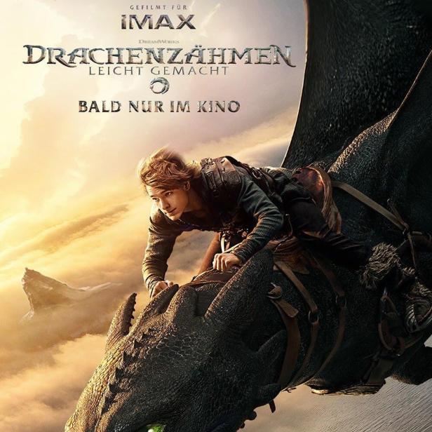 Ein junger Mann reitet auf einem schwarzen Drachen vor einer bewölkten Landschaft.