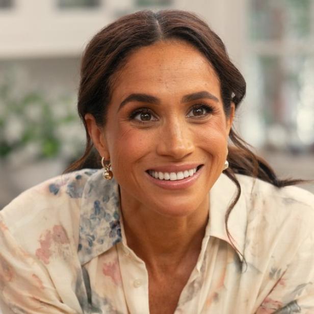 Ein Porträt von Herzogin Meghan in einem floralen Hemd, lächelnd.